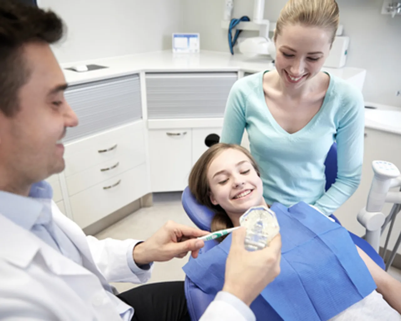 Dentist educating young patient who is smiling