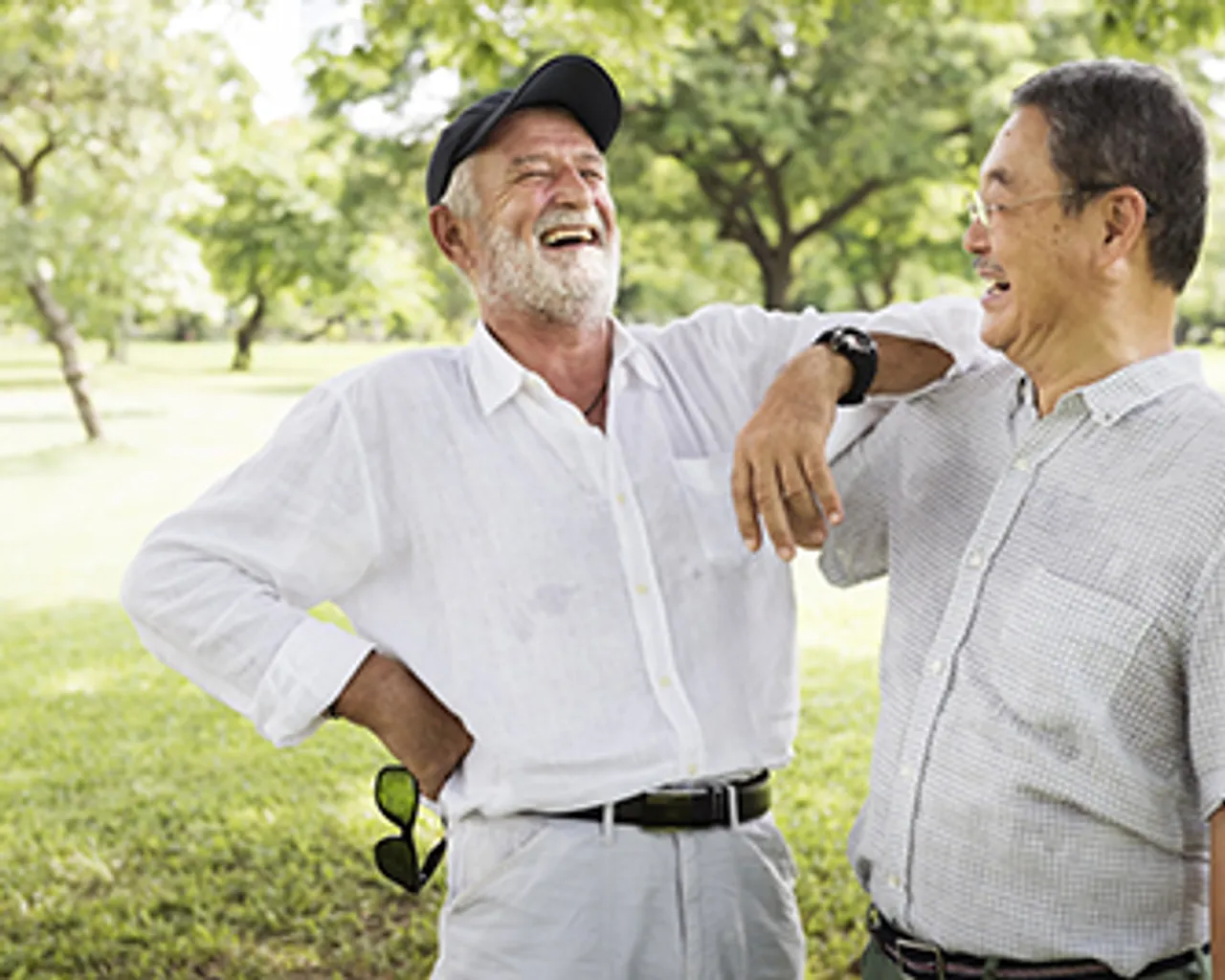 Two older friends laughing in the park